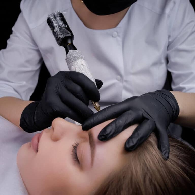 Permanent makeup artist performing a professional eyebrow procedure on a client using advanced PMU equipment.